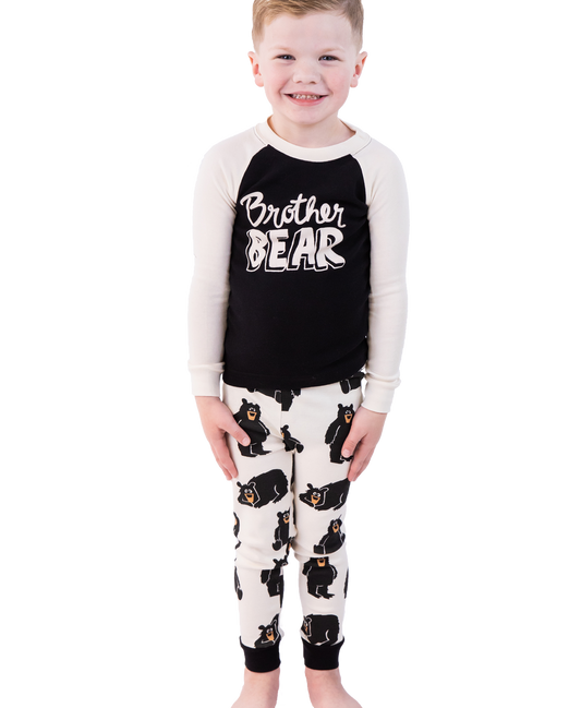 Child wearing a 'Brother Bear' pajama set with black and white design on a white background
