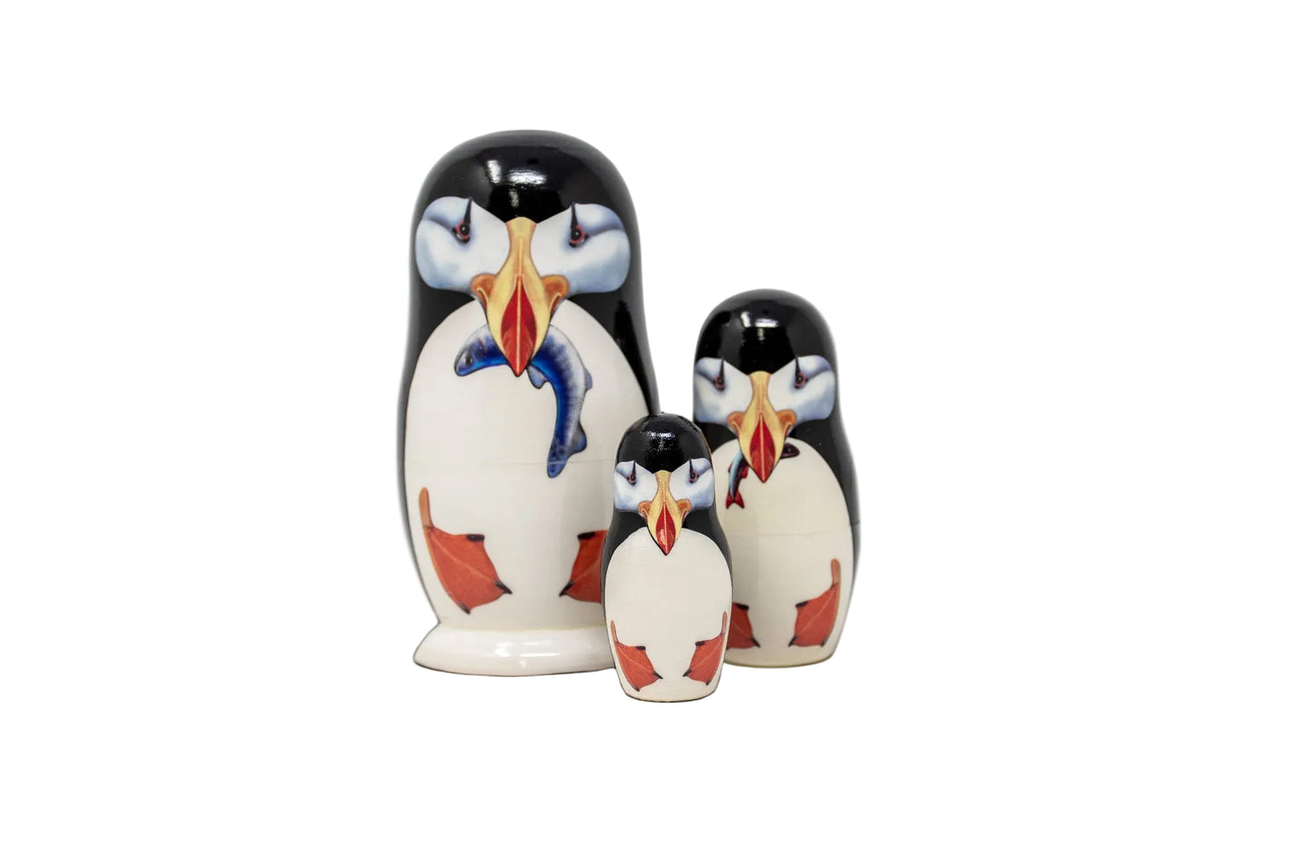 Three nesting dolls with puffin design on a white background