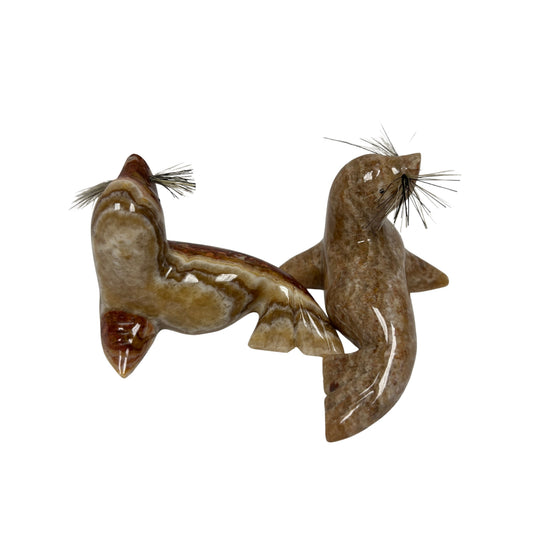 Two figurines of seals on a white background