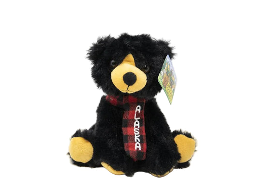 Black bear plush toy with a red plaid scarf and a tag