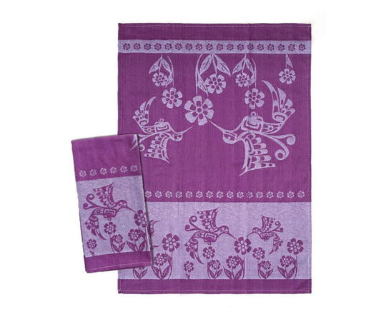 Two purple tea towels with floral and bird patterns on a white background