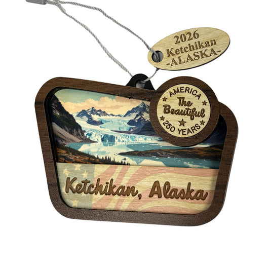 Decorative ornament with Ketchikan, Alaska landscape and 'America the Beautiful' text.