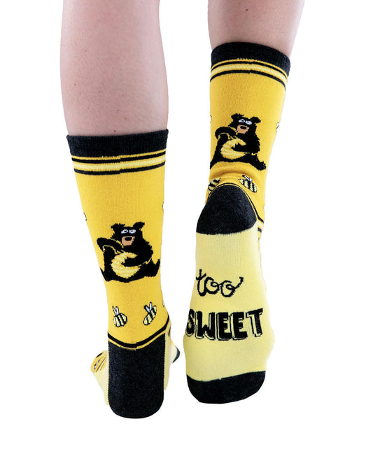Yellow socks with black accents and bear graphics worn by a person on a white background