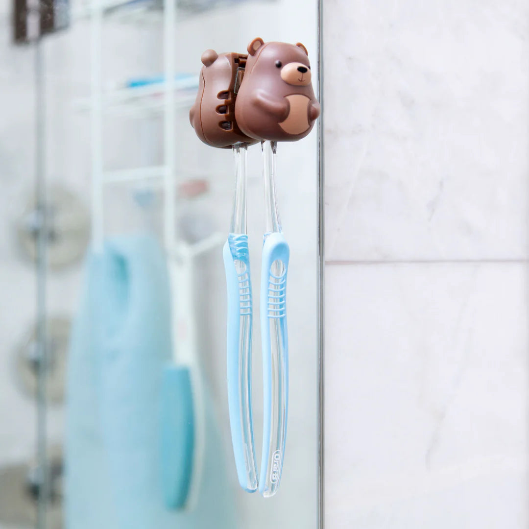 Bear-shaped toothbrush holder with a blue toothbrush on a bathroom mirror.