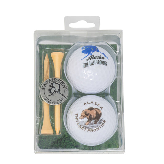 Two golf balls with Alaska-themed graphics and a wooden tee in a clear packaging sleeve