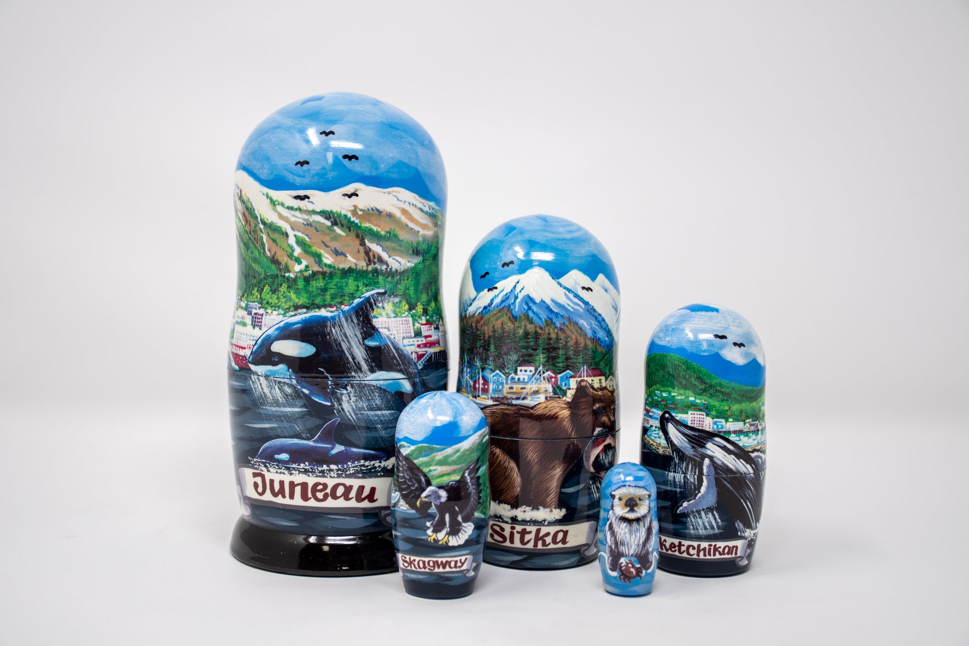 Set of Russian nesting dolls with Alaska-themed images on a white background