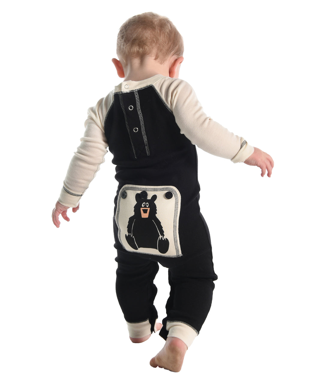 Child wearing a black and white one piece with a cartoon bear 
