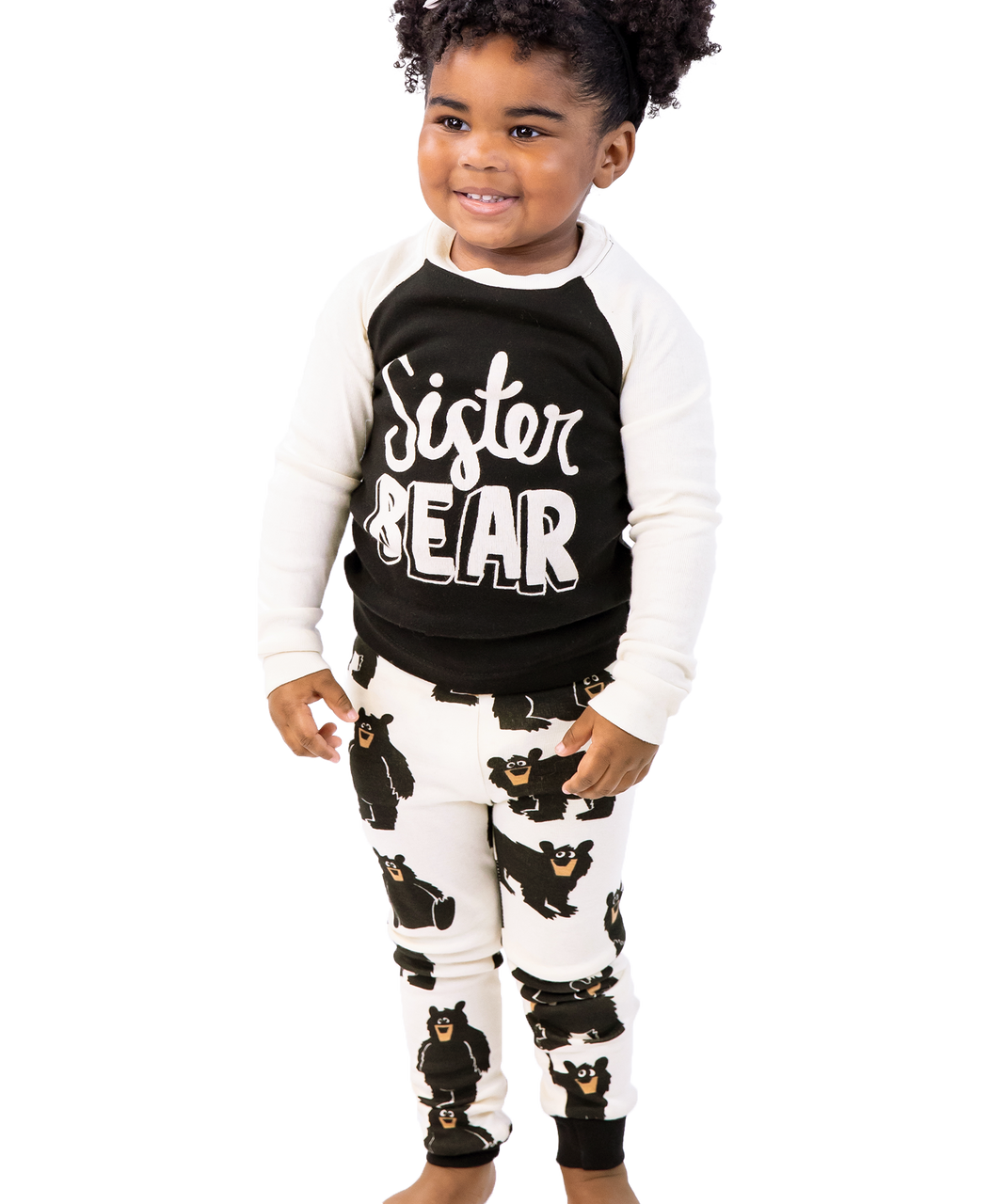 Child wearing a 'Sister Bear' shirt and pajama set on a white background