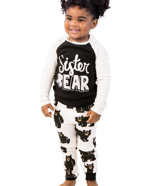 Child wearing a 'Sister Bear' shirt and pajama set on a white background