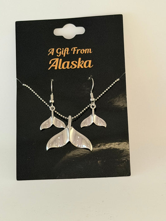 Silver whale tail earrings and necklace on black background
