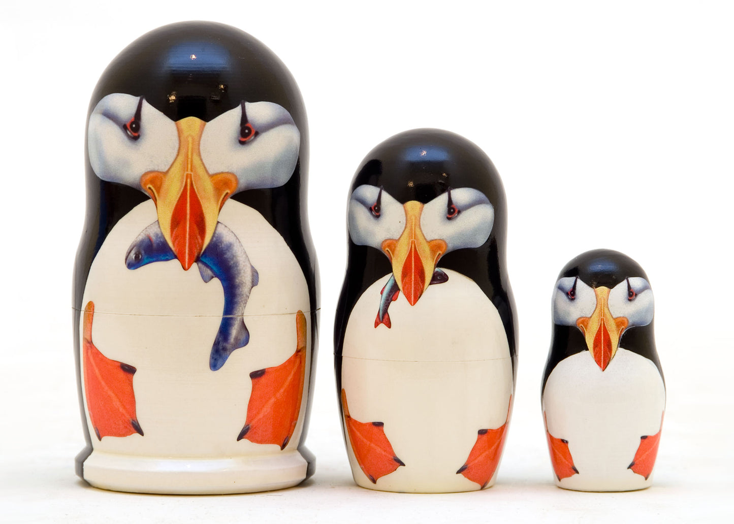Set of three nesting dolls with puffin design on a white background