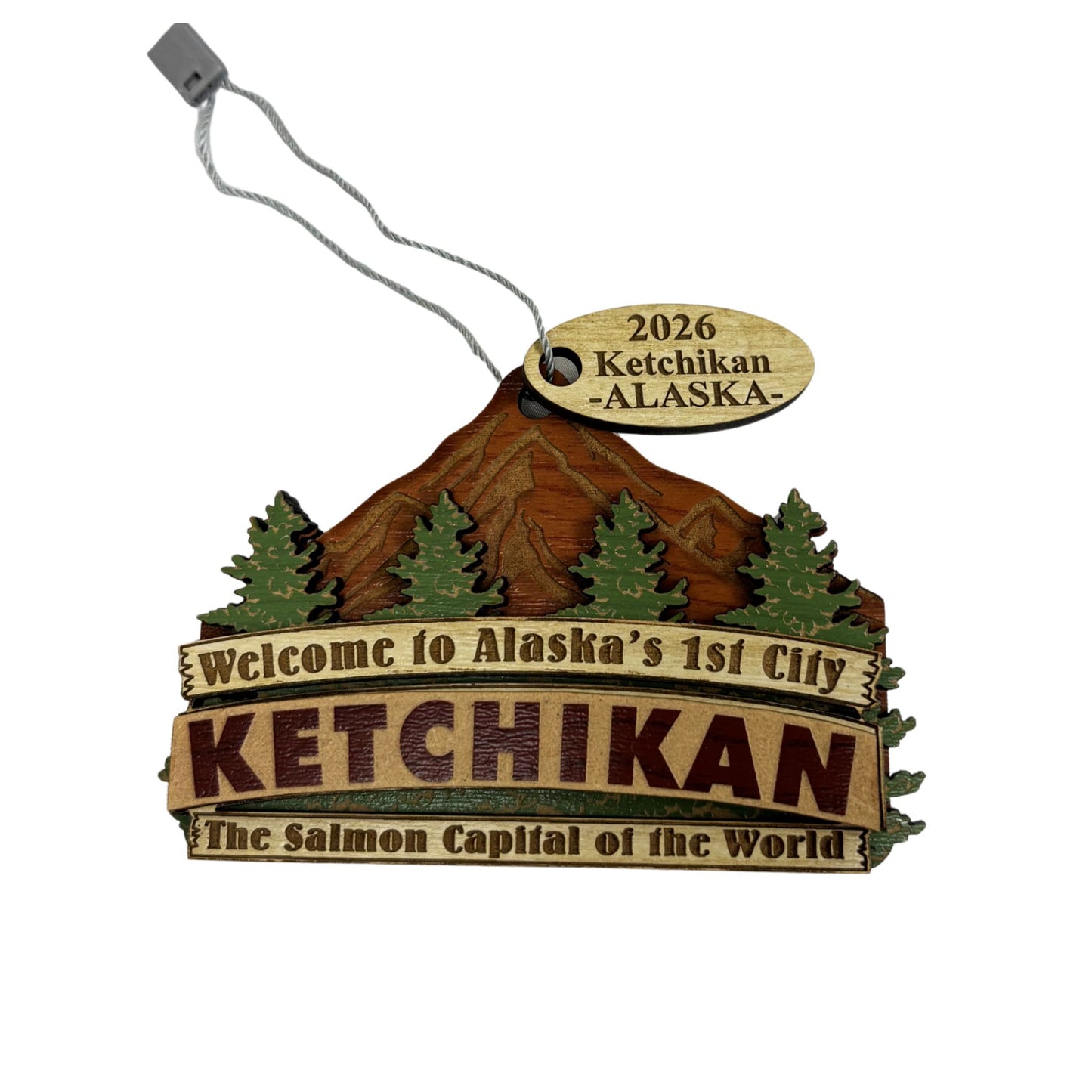 Wooden ornament with Ketchikan, Alaska welcome sign with mountain and tree design.