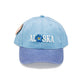 Light blue cap with 'Alaska' and flower design on a white background