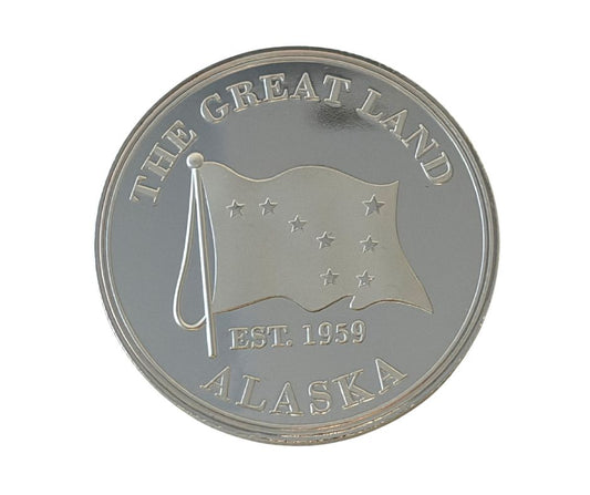 Silver coin with 'The Great Land Alaska' text and flag design 