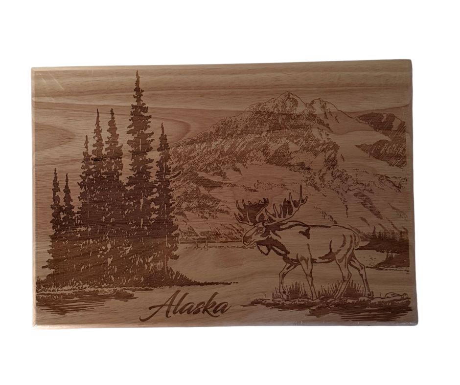 Wooden cutting board with engraved landscape and moose design, featuring the word 'Alaska'.
