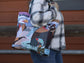 Person holding a tote bag with Alaska design and plaid shirt.