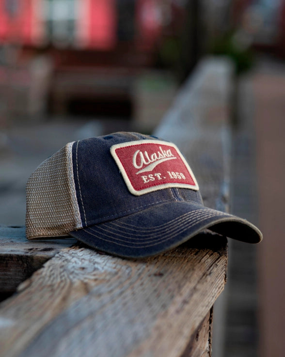 Ball cap with a red and white patch on a wooden surface