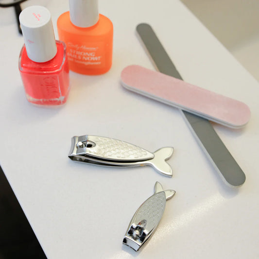 Nail care tools including nail clippers, a file, and nail polish on a white surface.