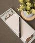 Notepad with donkey illustrations and a pen on a brown surface with a plant in the background