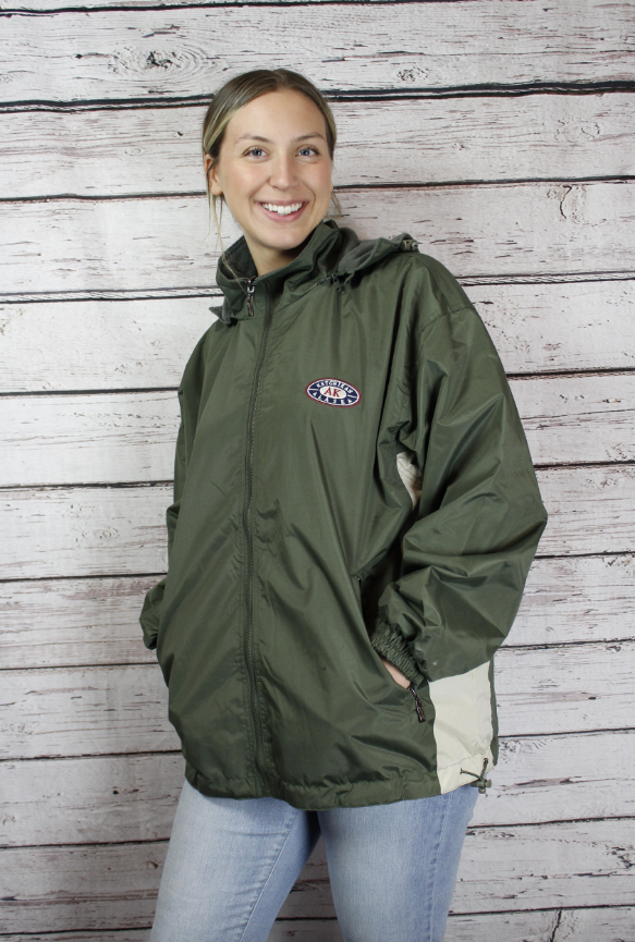 Woman wearing a green jacket with a logo against a wooden background