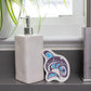 Soap dispenser on a bathroom counter with an eco sponge featuring a purple and blue form line whale design