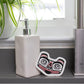 White soap dispenser with an Eco Sponge leaning on it, with a formline matriarch bear design 