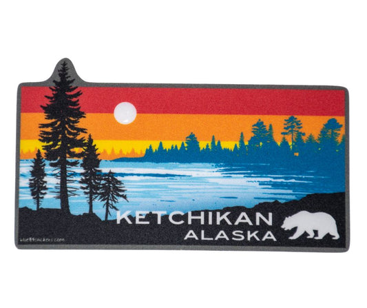 Silhouette of pine trees and a bear against a colorful sunset lake scene sticker